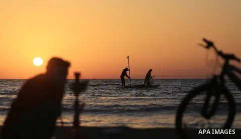 Palestinains ride a boat during sunset at the beach of the Mediterranean sea on the coast of Gaza city on April 17, 2016. Photo by Yasser Qudih