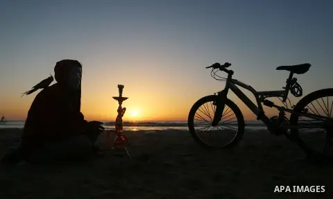A Palestinian youth smokes flavoured tobacco water pipes or 'shisha' during sunset at the beach of the Mediterranean sea on the coast of Gaza city on April 17, 2016. Photo by Yasser Qudih
