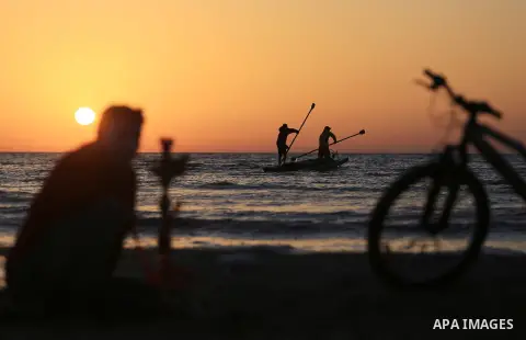 Palestinains ride a boat during sunset at the beach of the Mediterranean sea on the coast of Gaza city on April 17, 2016. Photo by Yasser Qudih