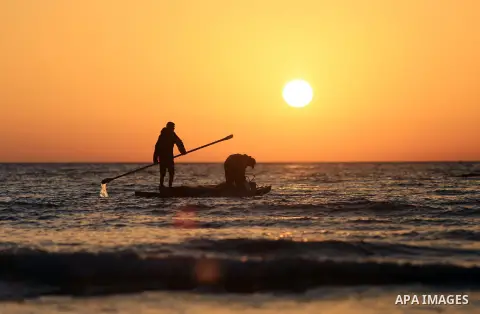 Palestinains ride a boat during sunset at the beach of the Mediterranean sea on the coast of Gaza city on April 17, 2016. Photo by Yasser Qudih