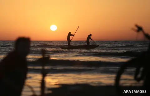 Palestinains ride a boat during sunset at the beach of the Mediterranean sea on the coast of Gaza city on April 17, 2016. Photo by Yasser Qudih