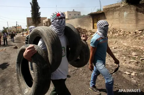 A Palestinian protester carries tires during clashes with Israeli security forces following a weekly demonstration against the expropriation of Palestinian land by Israel in the village of Kfar Qaddum, near Nablus, in th...