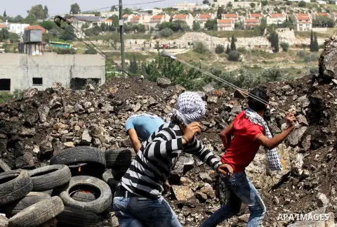Palestinian protesters use a slingshot to hurl stones towards Israeli security forces during clashes following a weekly demonstration against the expropriation of Palestinian land by Israel in the village of Kfar Qaddum,...