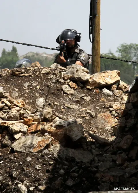A member of Israeli security forces takes aim as he holds a position during clashes with Palestinian protesters following a weekly demonstration against the expropriation of Palestinian land by Israel in the village of K...