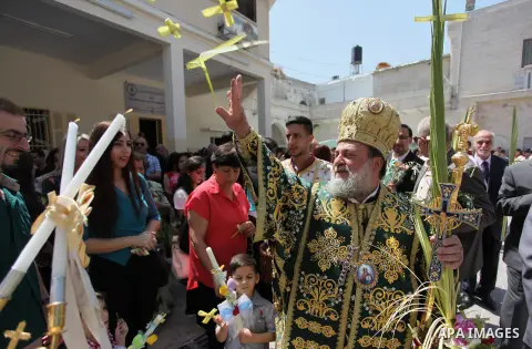 Reverend Archbishop of Tiberias, Alexios, gives the eucharist during the Greek Orthodox Christian Palm Sunday mass at St.Porphyrios Church in Gaza City, on April 24, 2016. Palm Sunday marks the triumphant return of Jesus...