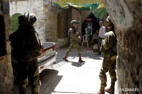 Israeli troops stand guard as Israeli settlers have a tour during the Jewish holiday of Passover in the West Bank city of Hebron, on April 25, 2016. Photo by Wisam Hashlamoun