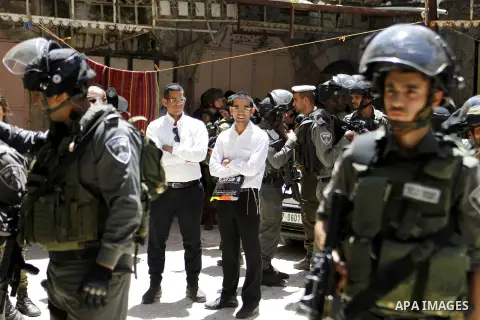 Israeli troops stand guard as Israeli settlers have a tour during the Jewish holiday of Passover in the West Bank city of Hebron, on April 25, 2016. Photo by Wisam Hashlamoun