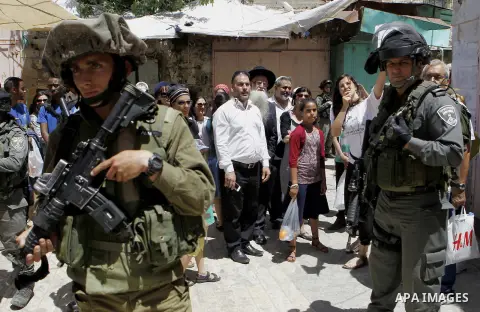 Israeli troops stand guard as Israeli settlers have a tour during the Jewish holiday of Passover in the West Bank city of Hebron, on April 25, 2016. Photo by Wisam Hashlamoun