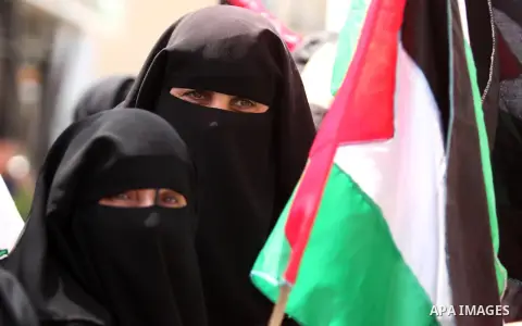Palestinian women hold national flags during a demonstration to calling for an end in the political division and the national reconciliation in Gaza city, on April 26, 2016. Photo by Ashraf Amra
