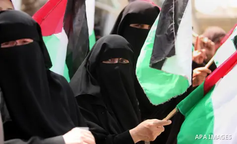 Palestinian women hold national flags during a demonstration to calling for an end in the political division and the national reconciliation in Gaza city, on April 26, 2016. Photo by Ashraf Amra