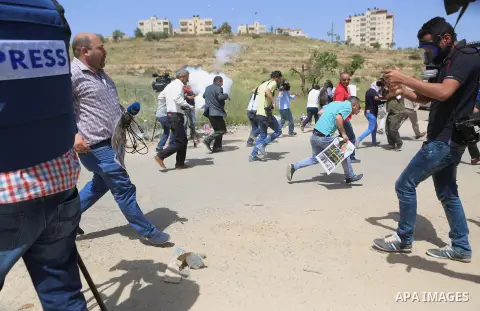 Palestinian journalists run for cover from a tear gas canister fired by Israeli troops during a protest calling for the release of Palestinian journalist Omar Nazal, who is held by Israel, near Israel's Ofer Prison near...