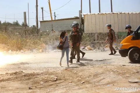 A Palestinian journalist runs for cover from a tear gas canister fired by Israeli troops during a protest calling for the release of Palestinian journalist Omar Nazal, who is held by Israel, near Israel's Ofer Prison nea...
