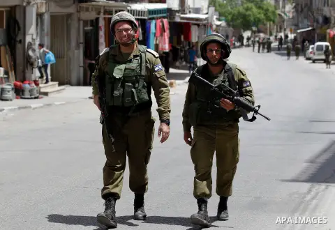 Israeli troops stand guard as Israeli settlers have a tour during the Jewish holiday of Passover in the West Bank city of Hebron, on April 26, 2016. Photo by Wisam Hashlamoun
