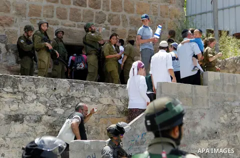 Israeli troops stand guard as Israeli settlers have a tour during the Jewish holiday of Passover in the West Bank city of Hebron, on April 26, 2016. Photo by Wisam Hashlamoun