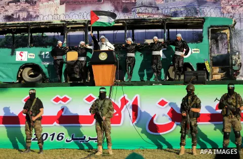 Palestinian Hamas militants march in front of a mock burnt Israeli bus during an anti-Israel rally in Gaza city April 28, 2016. Photo by Mohammed Asad
