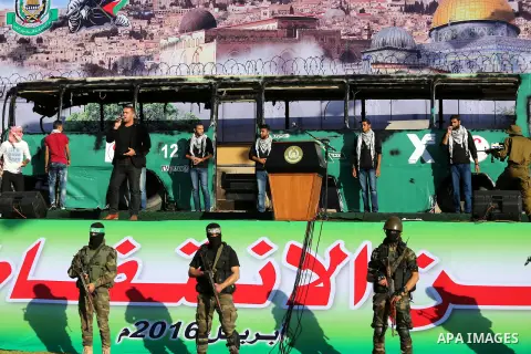 Palestinian Hamas militants march in front of a mock burnt Israeli bus during an anti-Israel rally in Gaza city April 28, 2016. Photo by Mohammed Asad