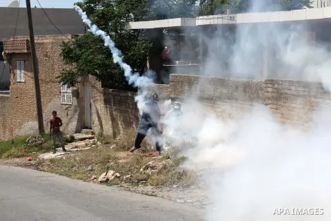 A Palestinian protester throws back a tear gas canister fired by Israeli security forces during clashes following a demonstration against the expropriation of Palestinian land by Israel on April 29, 2016 in the village o...