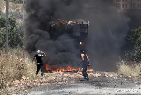 Palestinian protesters hurl stones towards a digger operated by Israeli security forces during clashes following a demonstration against the expropriation of Palestinian land by Israel on April 29, 2016 in the village of...