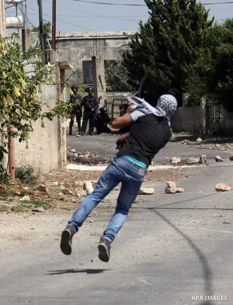 A Palestinian protester uses a slingshot to hurl stones towards Israeli security forces during clashes following a demonstration against the expropriation of Palestinian land by Israel on April 29, 2016 in the village of...