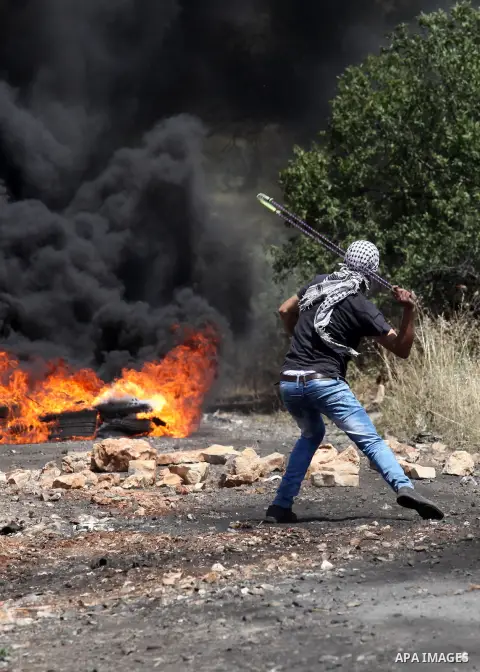 A Palestinian protester hurls stones towards a digger operated by Israeli security forces during clashes following a demonstration against the expropriation of Palestinian land by Israel on April 29, 2016 in the village...