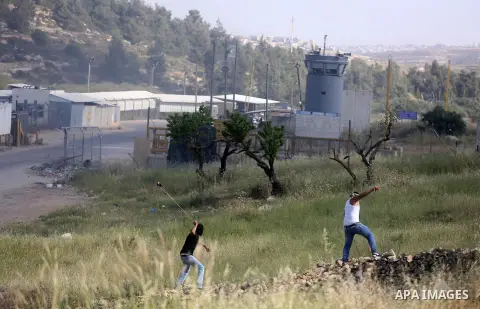 Palestinian protesters use a slingshot to hurl stones towards Israeli security forces during clashes on April 29, 2016, following a demonstration in solidarity with Palestinian prisoners held in Israeli jails, outside th...