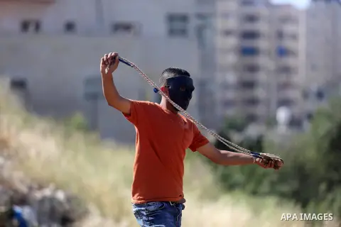 A Palestinian protester uses a slingshot to hurl stones towards Israeli security forces during clashes on April 29, 2016, following a demonstration in solidarity with Palestinian prisoners held in Israeli jails, outside...