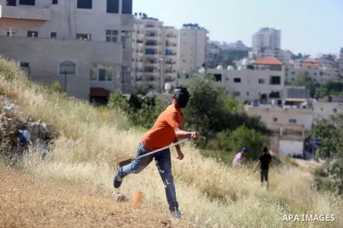 A Palestinian protester uses a slingshot to hurl stones towards Israeli security forces during clashes on April 29, 2016, following a demonstration in solidarity with Palestinian prisoners held in Israeli jails, outside...