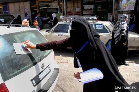 Palestinian women supporting Hamas movement distribute posters during awareness campaign against collaborate with Israel, in Rafah in southern Gaza strip, on April 30, 2016. Photo by Abed Rahim Khatib