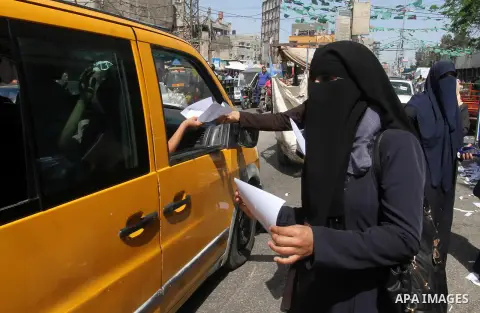 Palestinian women supporting Hamas movement distribute posters during awareness campaign against collaborate with Israel, in Rafah in southern Gaza strip, on April 30, 2016. Photo by Abed Rahim Khatib