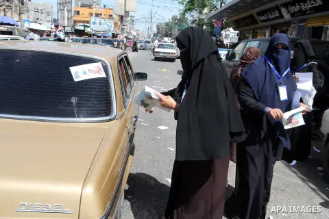 Palestinian women supporting Hamas movement distribute posters during awareness campaign against collaborate with Israel, in Rafah in southern Gaza strip, on April 30, 2016. Photo by Abed Rahim Khatib