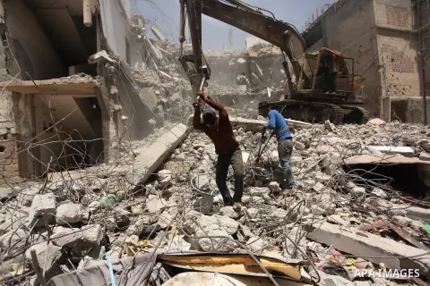 Palestinian men work on the remains of a building destroyed during the recent Israeli war 2014, in Shijaiyah neighborhood in the east of Gaza city, on April 30, 2016. Israel’s punitive ban on cement imports into the Gaza...