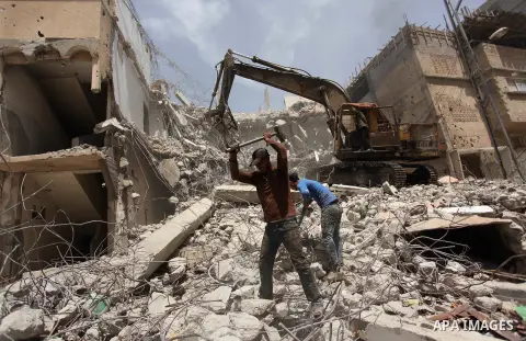 Palestinian men work on the remains of a building destroyed during the recent Israeli war 2014, in Shijaiyah neighborhood in the east of Gaza city, on April 30, 2016. Israel’s punitive ban on cement imports into the Gaza...