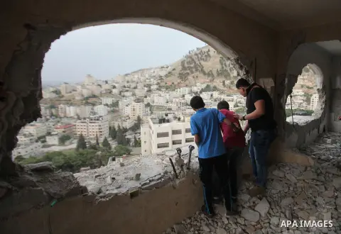 Palestinians look at the damage in the West Bank city of Nablus on May 3, 2016, after Israeli forces destroyed the house of Zaid Amer, a Palestinian man accused of taking part in the killing of a Jewish settler couple ne...