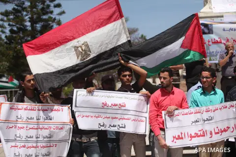 Palestinians hold banners during a protest demanding the Egyptian authorities for the opening of the Rafah crossing, in Gaza, on May 4, 2016. Photo by Ashraf Amra