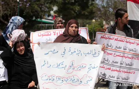 Palestinians hold banners during a protest demanding the Egyptian authorities for the opening of the Rafah crossing, in Gaza, on May 4, 2016. Photo by Ashraf Amra