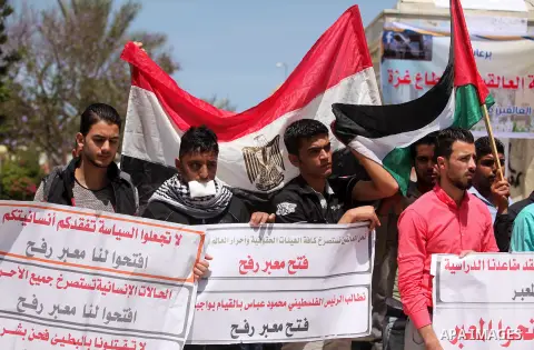 Palestinians hold banners during a protest demanding the Egyptian authorities for the opening of the Rafah crossing, in Gaza, on May 4, 2016. Photo by Ashraf Amra
