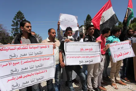 Palestinians hold banners during a protest demanding the Egyptian authorities for the opening of the Rafah crossing, in Gaza, on May 4, 2016. Photo by Ashraf Amra