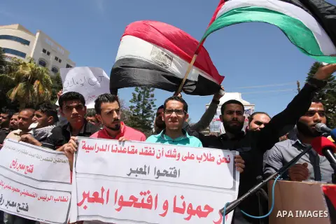 Palestinians hold banners during a protest demanding the Egyptian authorities for the opening of the Rafah crossing, in Gaza, on May 4, 2016. Photo by Ashraf Amra