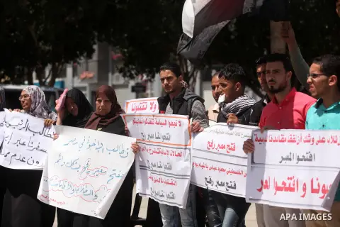 Palestinians hold banners during a protest demanding the Egyptian authorities for the opening of the Rafah crossing, in Gaza, on May 4, 2016. Photo by Ashraf Amra