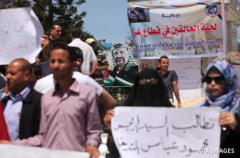 Palestinians hold banners during a protest demanding the Egyptian authorities for the opening of the Rafah crossing, in Gaza, on May 4, 2016. Photo by Ashraf Amra