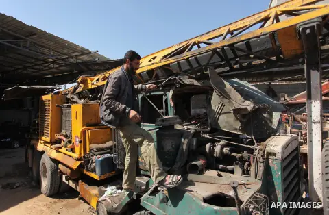 A Palestinian man inspects a damaged vehicle at his workshop after it was hit by an Israeli air strike in Gaza City, in the early hours of May 5, 2016. Israeli air strikes hit four Hamas sites in Gaza overnight, the mili...