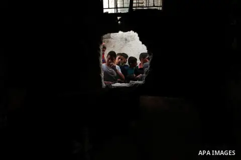 Palestinian children look through the window of burnt house after a candle caused a fire at the al-Hendi family's home at the al-Shati refugee camp in Gaza City on May 7, 2016. Photo by Ashraf Amra