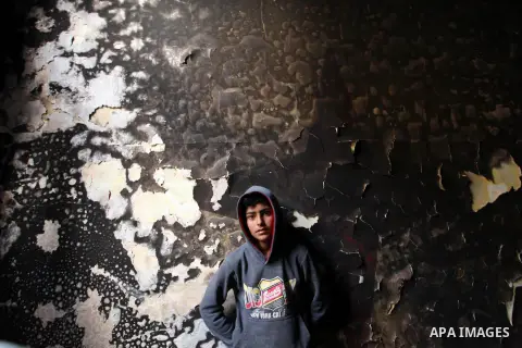 A Palestinian boy looks at the charred walls of a house after a candle caused a fire at the al-Hendi family's home at the al-Shati refugee camp in Gaza City on May 7, 2016. Photo by Ashraf Amra