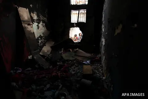 Palestinian children look through the window of burnt house after a candle caused a fire at the al-Hendi family's home at the al-Shati refugee camp in Gaza City on May 7, 2016. Photo by Ashraf Amra