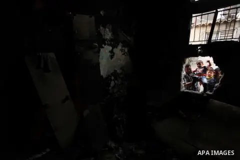 Palestinians look through the window of burnt house after a candle caused a fire at the al-Hendi family's home at the al-Shati refugee camp in Gaza City on May 7, 2016. Photo by Ashraf Amra