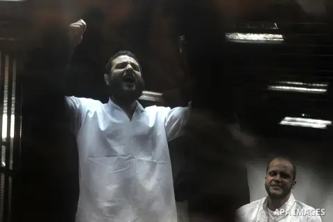 Defendants of Egyptian Muslim Brotherhood shot slogans from behind the defendant's bars during their trial at the police academy along with Egypt's ousted Islamist president Mohamed Morsi (unseen) in Cairo on May 7, 2016...