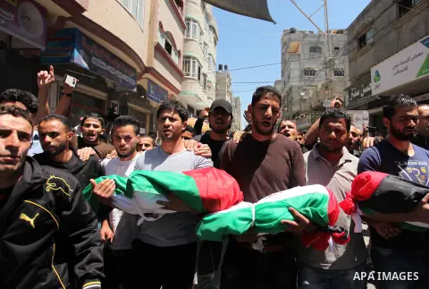 Palestinians carry the bodies of three children from the Abu Hindi family, who died in a fire caused by a candle at the family home, during their funeral at the al-Shati refugee camp in Gaza City on May 7, 2016. Photo by...