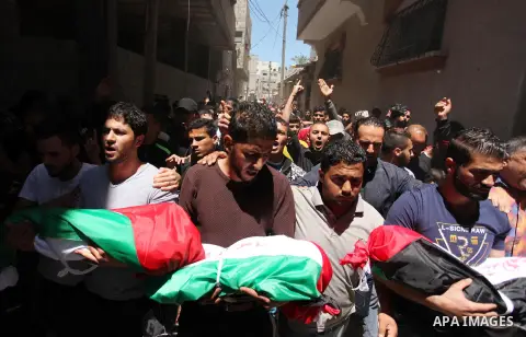Palestinians carry the bodies of three children from the Abu Hindi family, who died in a fire caused by a candle at the family home, during their funeral at the al-Shati refugee camp in Gaza City on May 7, 2016. Photo by...