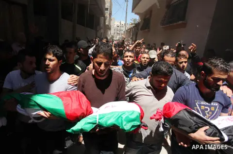 Palestinians carry the bodies of three children from the Abu Hindi family, who died in a fire caused by a candle at the family home, during their funeral at the al-Shati refugee camp in Gaza City on May 7, 2016. Photo by...