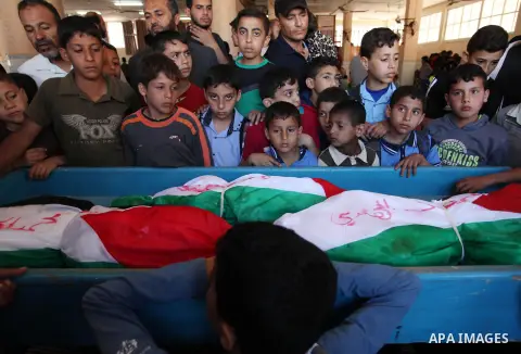 Palestinian children mourn next to the bodies of three boys from the al-Hindi family, who died in a fire caused by a candle at the family home, during their funeral at the al-Shati refugee camp in Gaza City on May 7, 201...